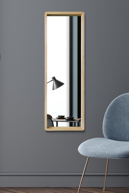 Solid oak box frame mirror hung portrait on a grey wall beside a blue velvet chair