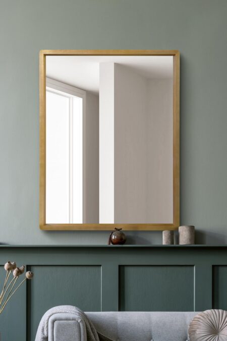 Natural oak framed mirror hung above a sage green panelled console in a living room