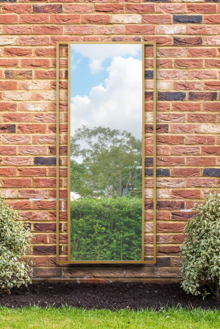 Extra large full length mirror with twin-bar gold frame mounted on a red brick garden wall