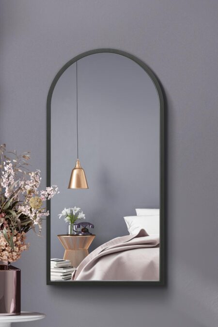 Tall arched mirror with slim dark frame styled in a softly lit grey bedroom