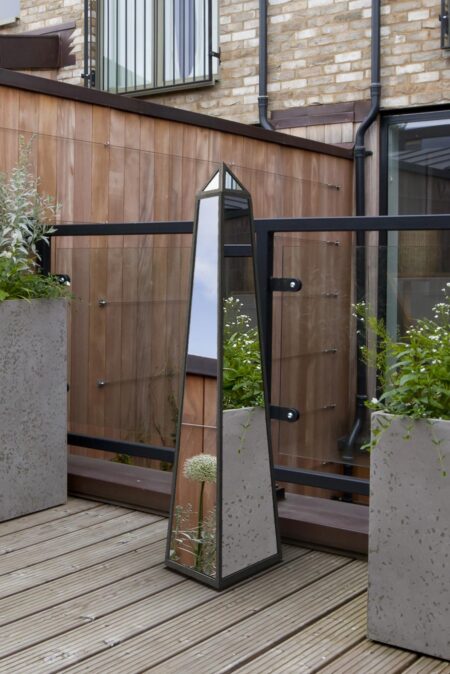 Free standing metal art obelisk mirror styled on a timber decked urban roof terrace